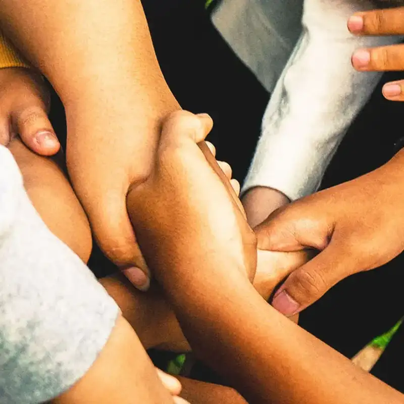 Viele Hände greifen ineinander, ein Symbol für Engagement das durch den Einsatz und die Zusammenarbeit vieler Einzelner getragen wird.
