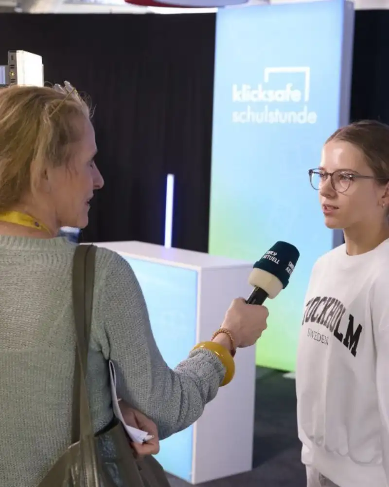 Eine Schülerin wird von einer Journalistin interviewt und dabei gefilmt.