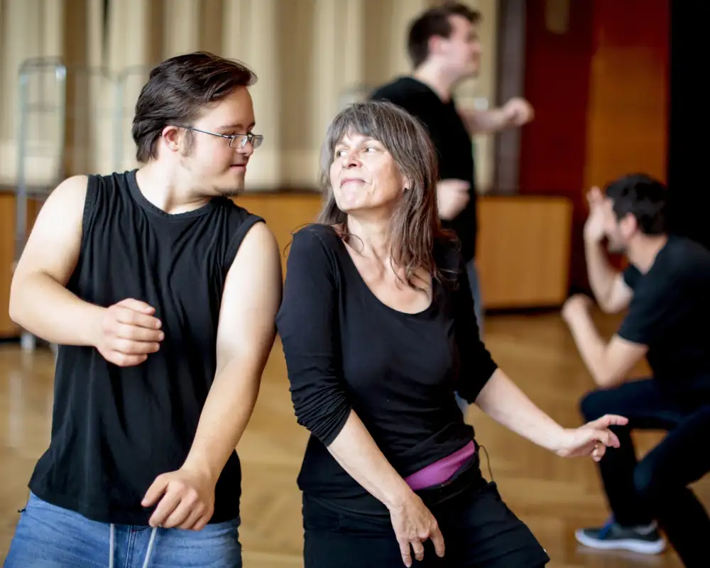Ein junger Mann mit Behinderung und eine Frau tanzen gemeinsam.