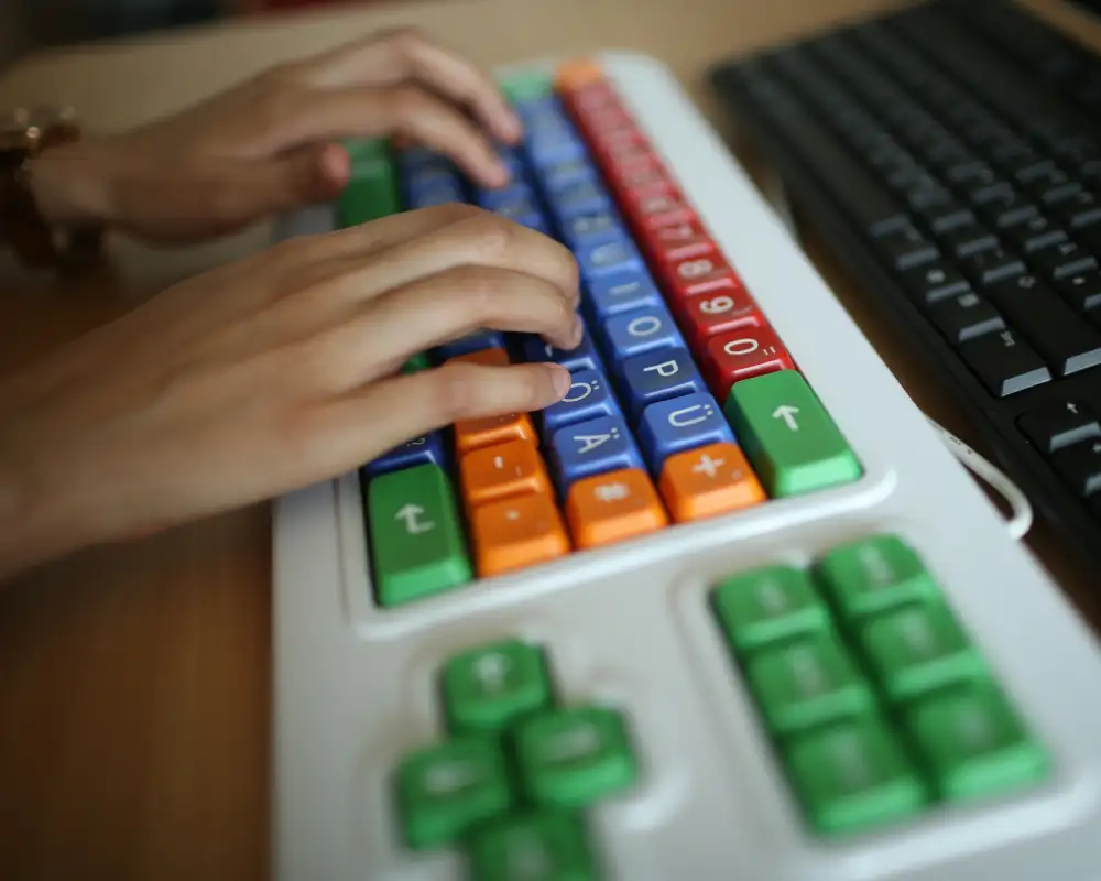 Zwei Hände auf einer bunten Tastatur.
