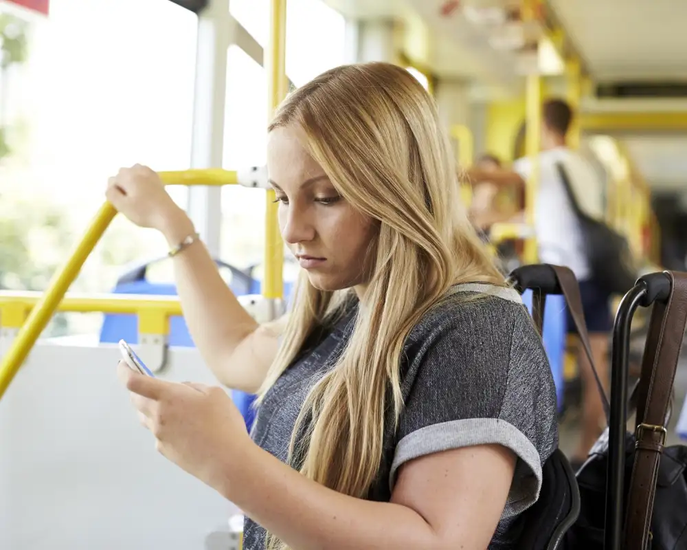 Eine Jugendlich im Rollstuhl befindet sich im Bus und schaut auf ihr Smartphone.