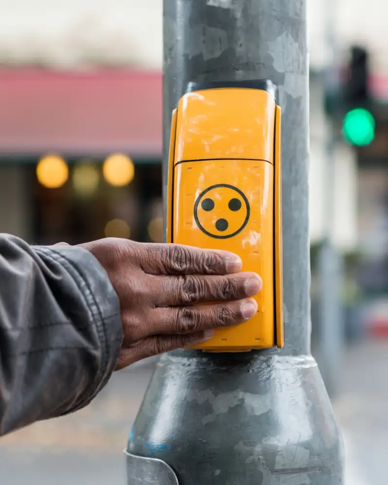 Eine Hand liegt auf einem Ampel-Anforderungstaster.