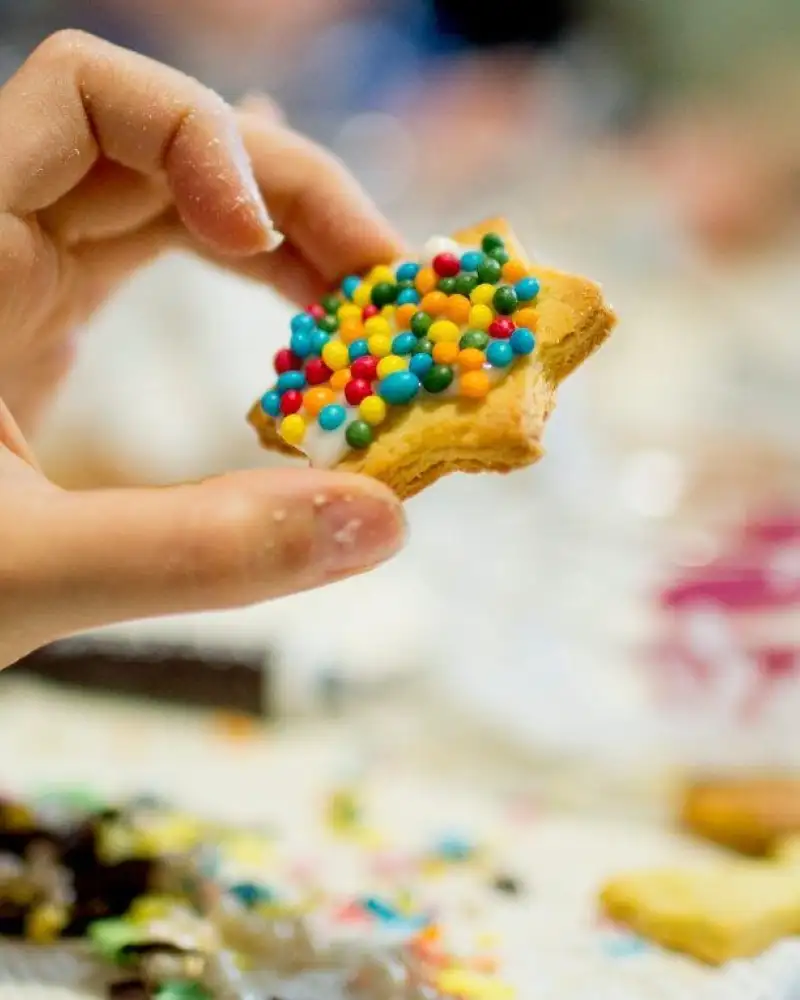 Eine Hand hält einen Keks mit bunten Streuseln.