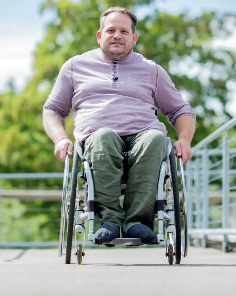 Ein Mann im Rollstuhl fährt über eine Rampe.