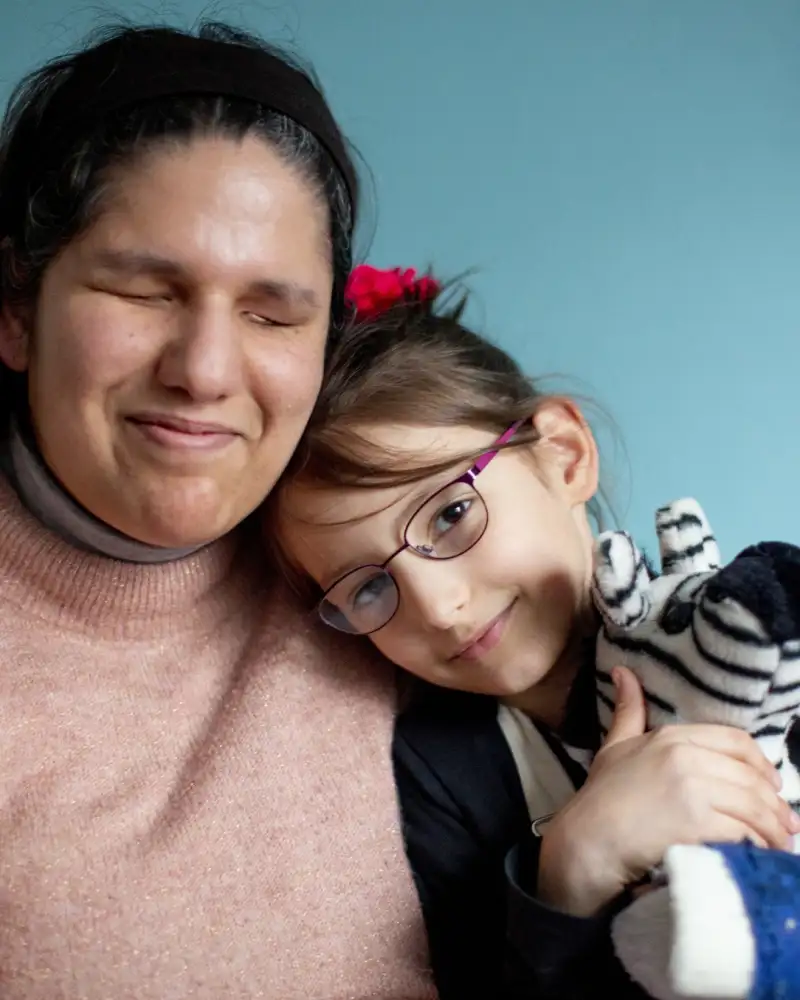 Eine blinde Frau hält ihre Tochter im Arm.