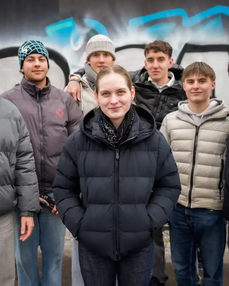 Gruppe Jugendlicher stehe vor Graphiti Wand und schauen mutig und entschlossen