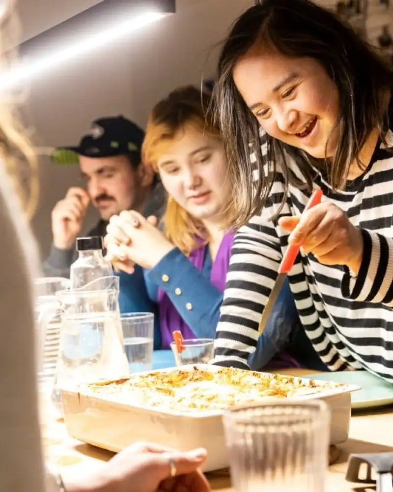 Eine Gruppe von jungen Menschen mit und ohne Behinderung isst gemeinsam zu Abend.