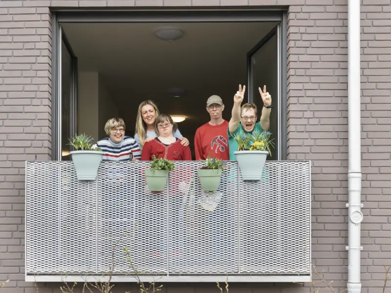 Fünf Personen mit und ohne Behinderung stehen auf einem Balkon.