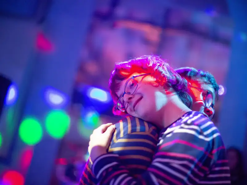 Eine Frau mit Downsyndrom eng umschlungen mit einem Mann auf der Tanzfläche.