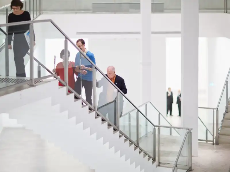 Mehrere Menschen mit und ohne Behinderung gehen eine Treppe herauf.