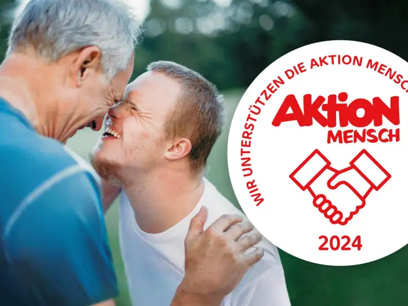 Ein Mann und ein Jugendlicher haben ihre Gesichter sehr dicht beieinander und lachen sich an. Daneben ist das Aktion Mensch-Siegel abgebildet.