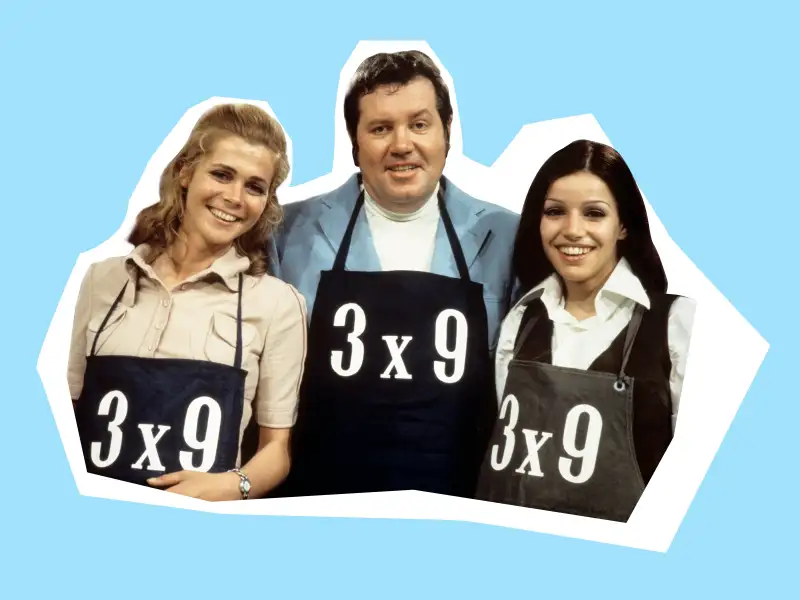Bild aus den 60ern: Wim Thoelke und zwei junge Frauen tragen eine schwarze Schürze mit der Aufschrift 3x9.
