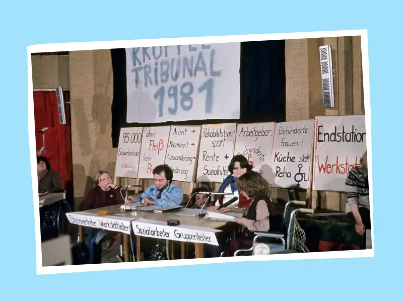 Vier Personen mit Behinderung halten eine Pressekonferenz ab. Über den Tischen hängt ein Plakat mit der Aufschrift "Krüppel-Tribunal 1981".