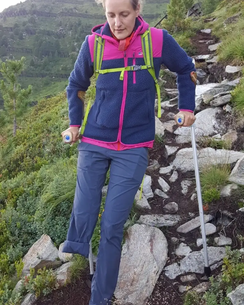 Eine junge einbeinige Frau auf Krücken beim Bergwandern.