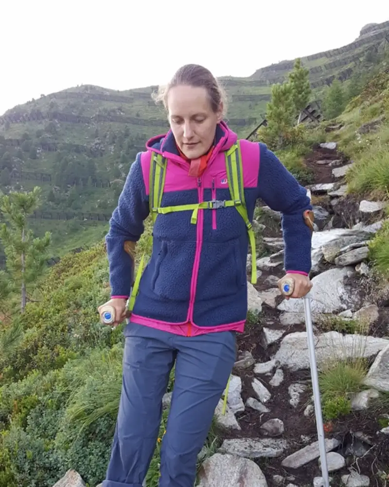 Eine junge einbeinige Frau auf Krücken beim Bergwandern.