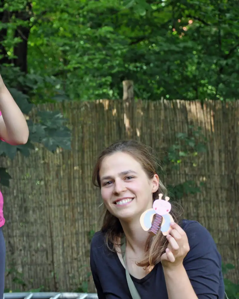 Ein Mädchen und eine junge Frau in einem Garten. Sie halten Selbstgebasteltes in der Hand.