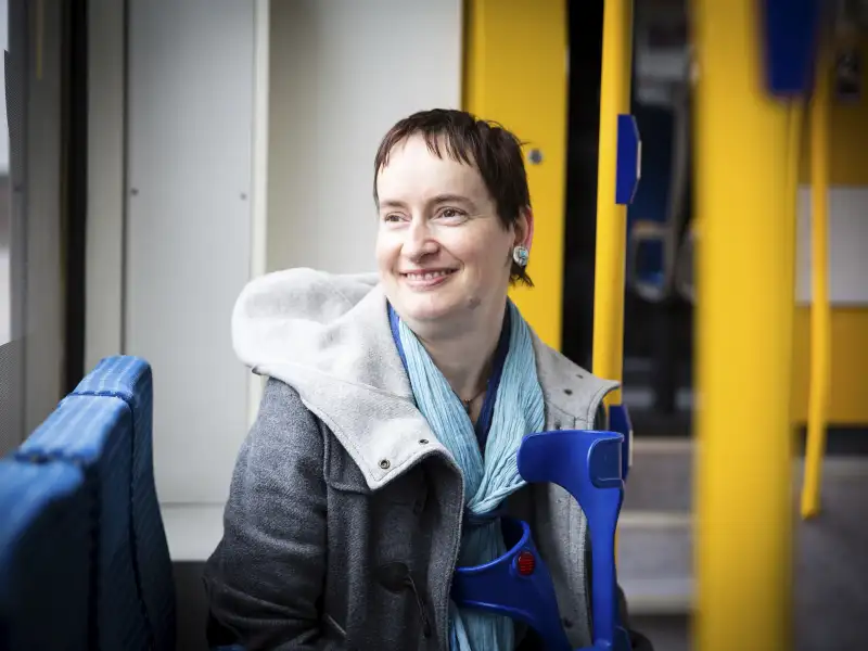 Agnes sitzt im Zug, lächelt und schaut aus dem Fenster.