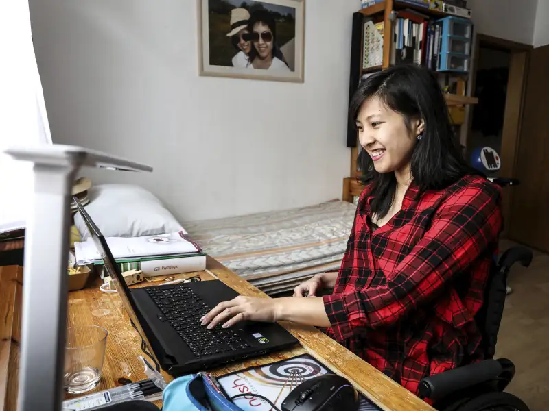 Simone schreibt an ihrem Laptop in ihrem Zimmer.