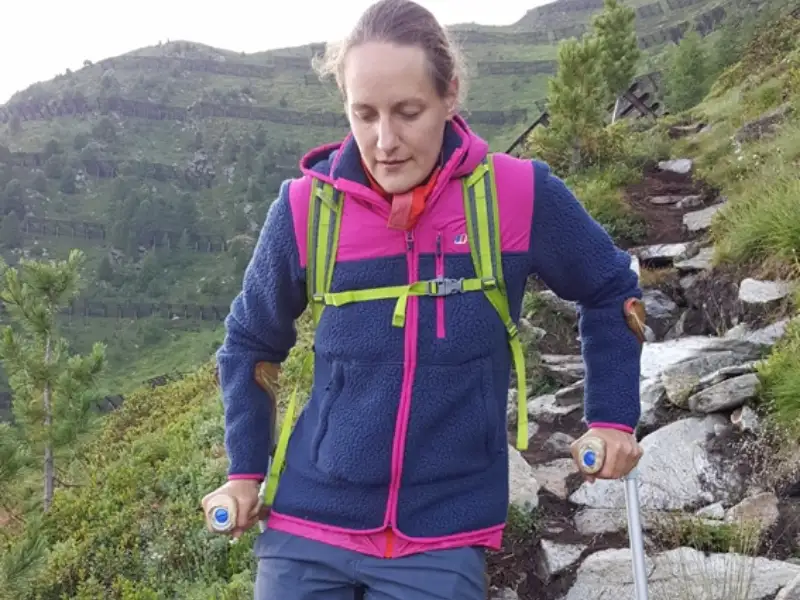 Eine junge einbeinige Frau auf Krücken beim Bergwandern.