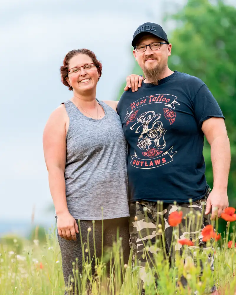 Aktion Mensch-Gewinnerin Sandra und ihr Mann Ingo stehen auf einer grünen Wiese und halten sich im Arm.