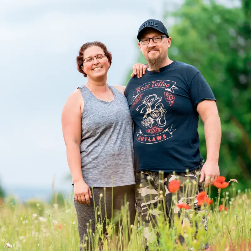 Aktion Mensch-Gewinnerin Sandra und ihr Mann Ingo stehen auf einer grünen Wiese und halten sich im Arm.