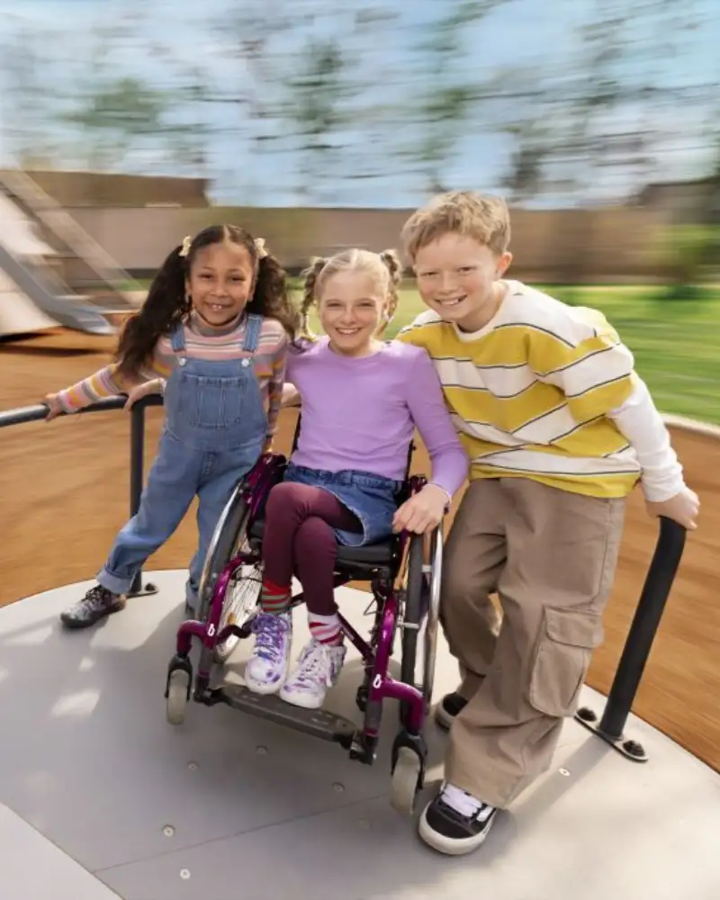 Drei Kinder auf einem Spielplatzkarussell.