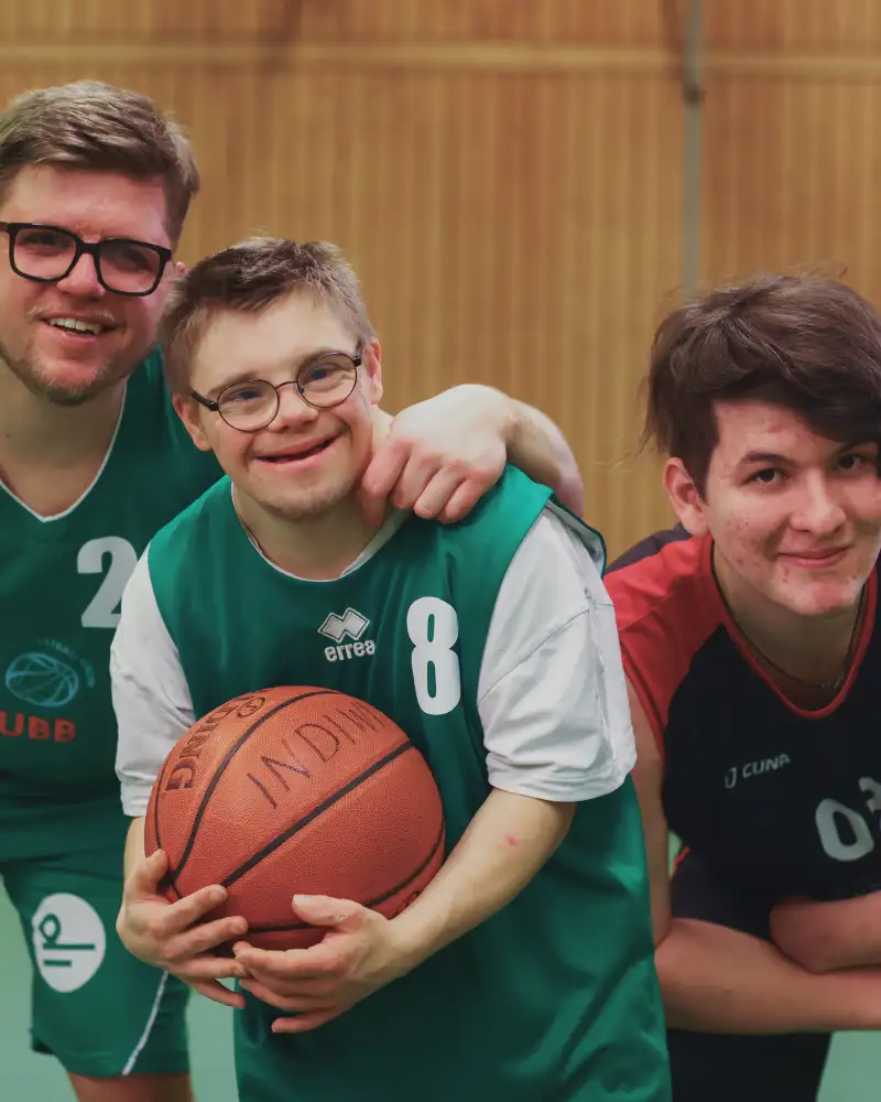 Drei Sportler, davon ein Basketballspieler mit Downsyndrom