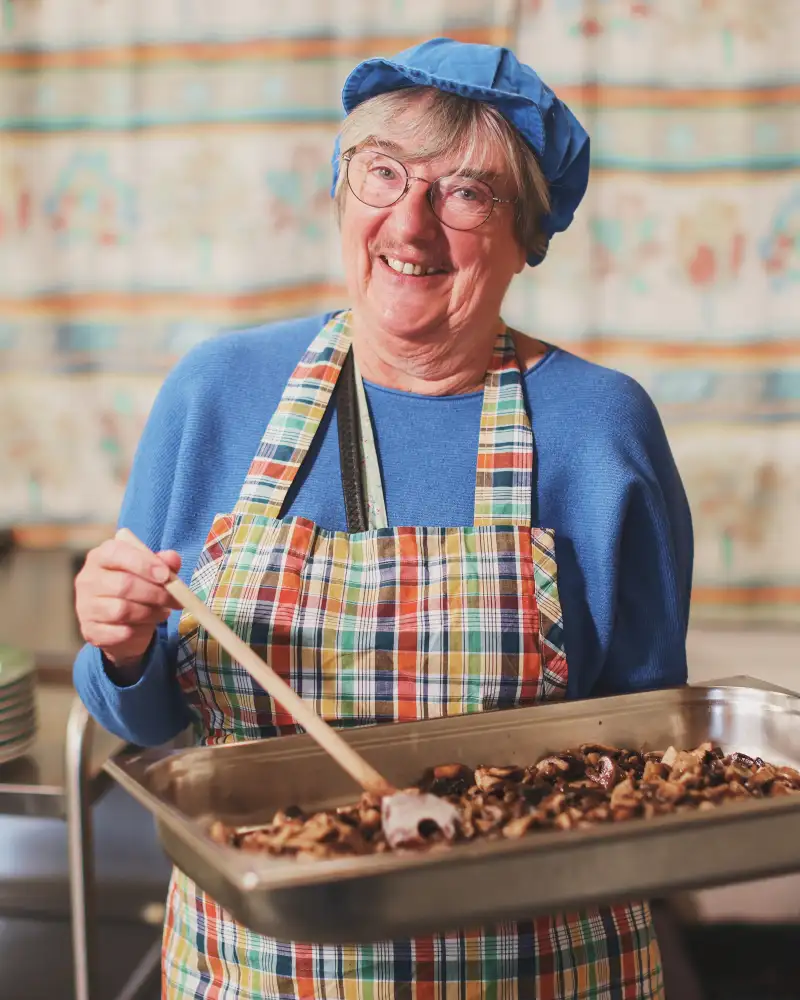 Eine Frau mit Schütze und Mütze mit einem Blech Essen