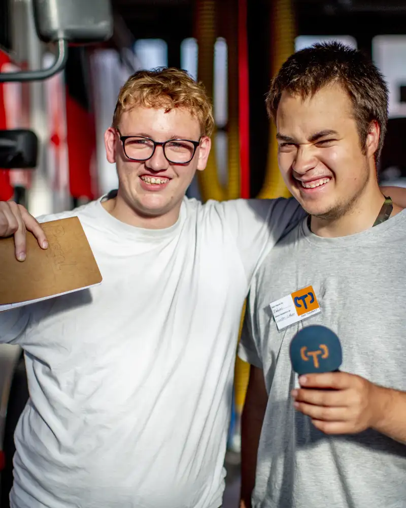 Zwei Männer vor Feuerwehrautos, einer trägt ein Mikro