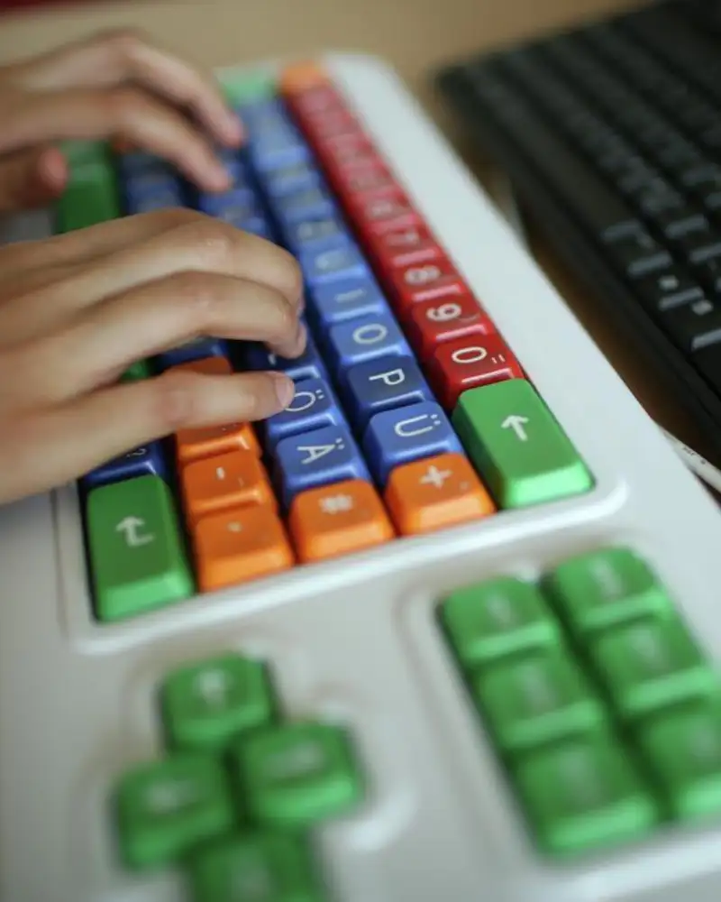 Zwei Hände auf einer bunten Tastatur