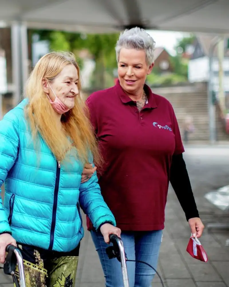 Zwei Frauen gehen spazieren. Eine von ihnen nutzt einen Rollator.