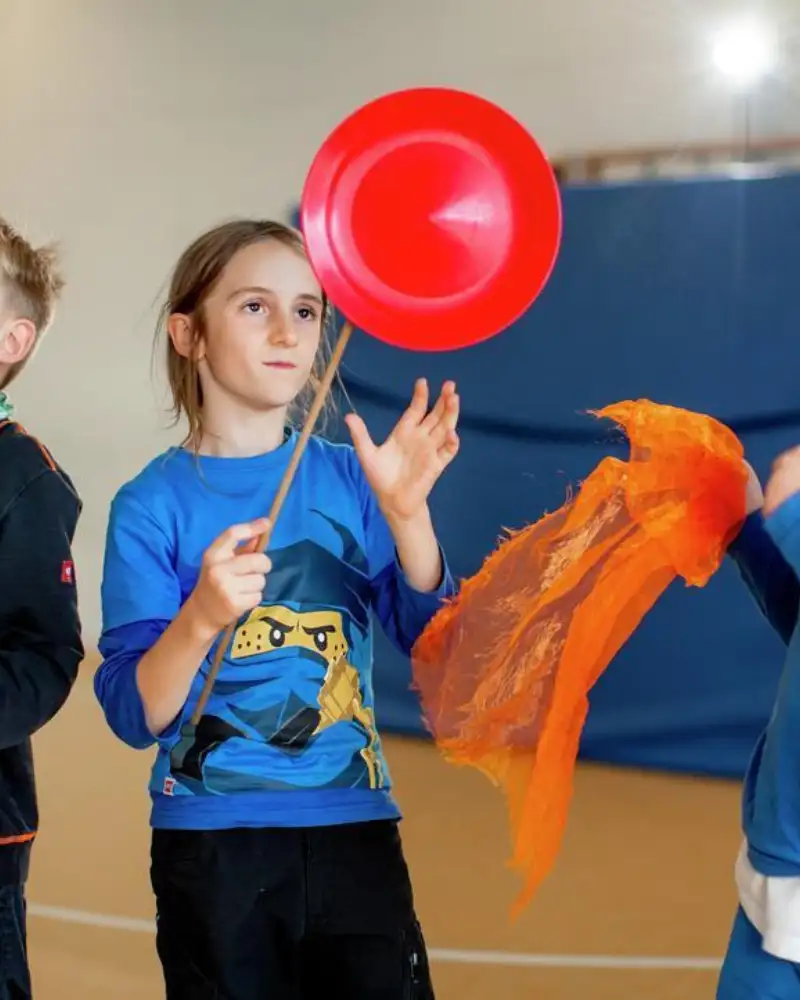Drei Kinder jonglieren mit Tellern und Tüchern.