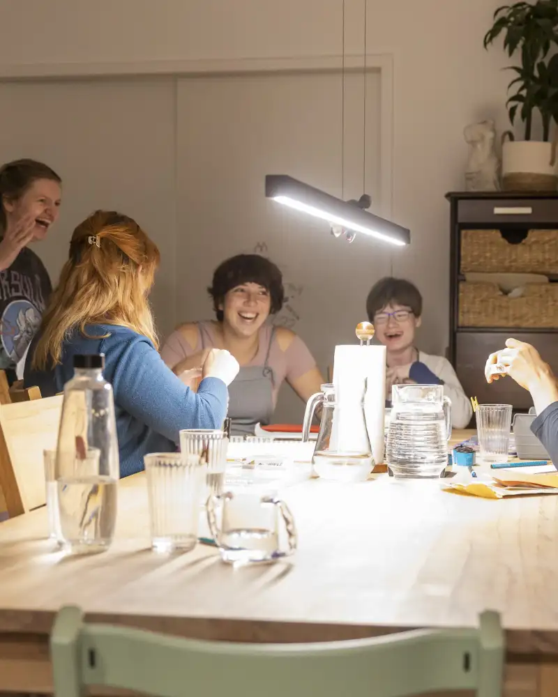 Fünf junge Frauen lachen an einem großen Tisch.