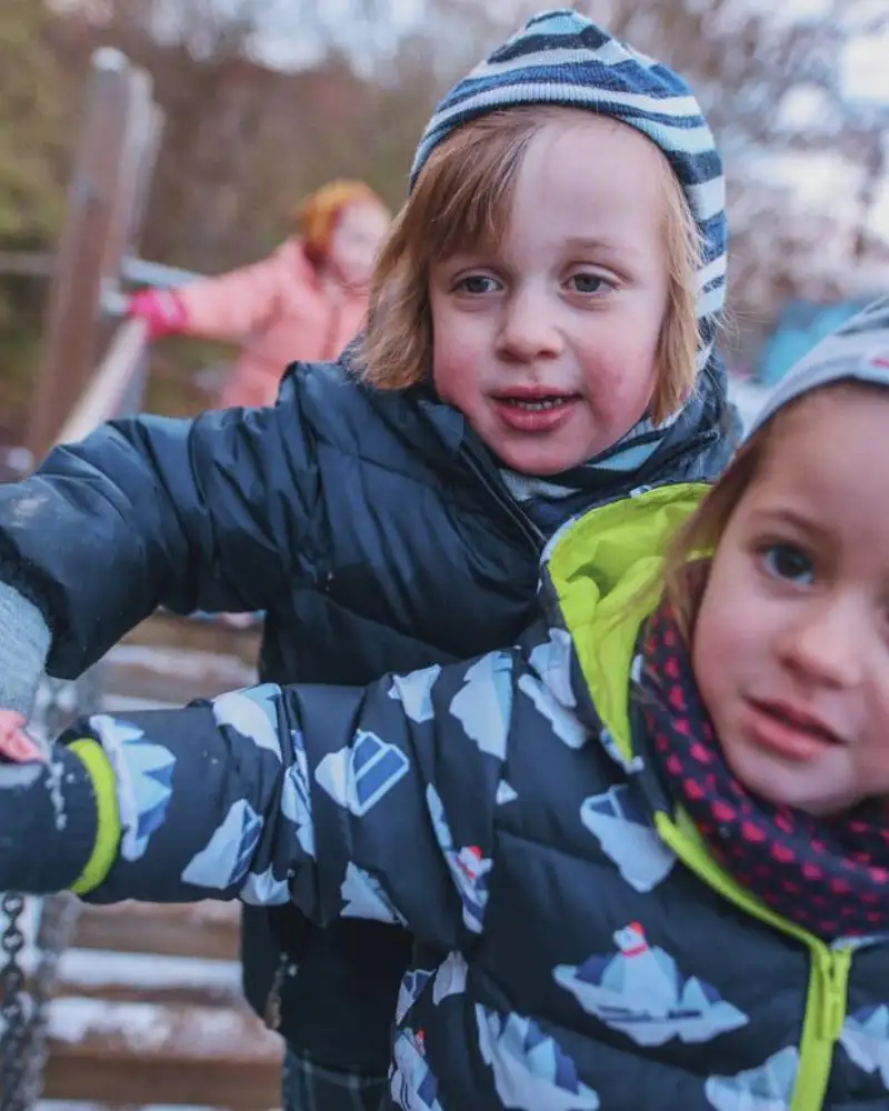 Zwei Kinder in Wintersachen auf einer Wackelbrücke.