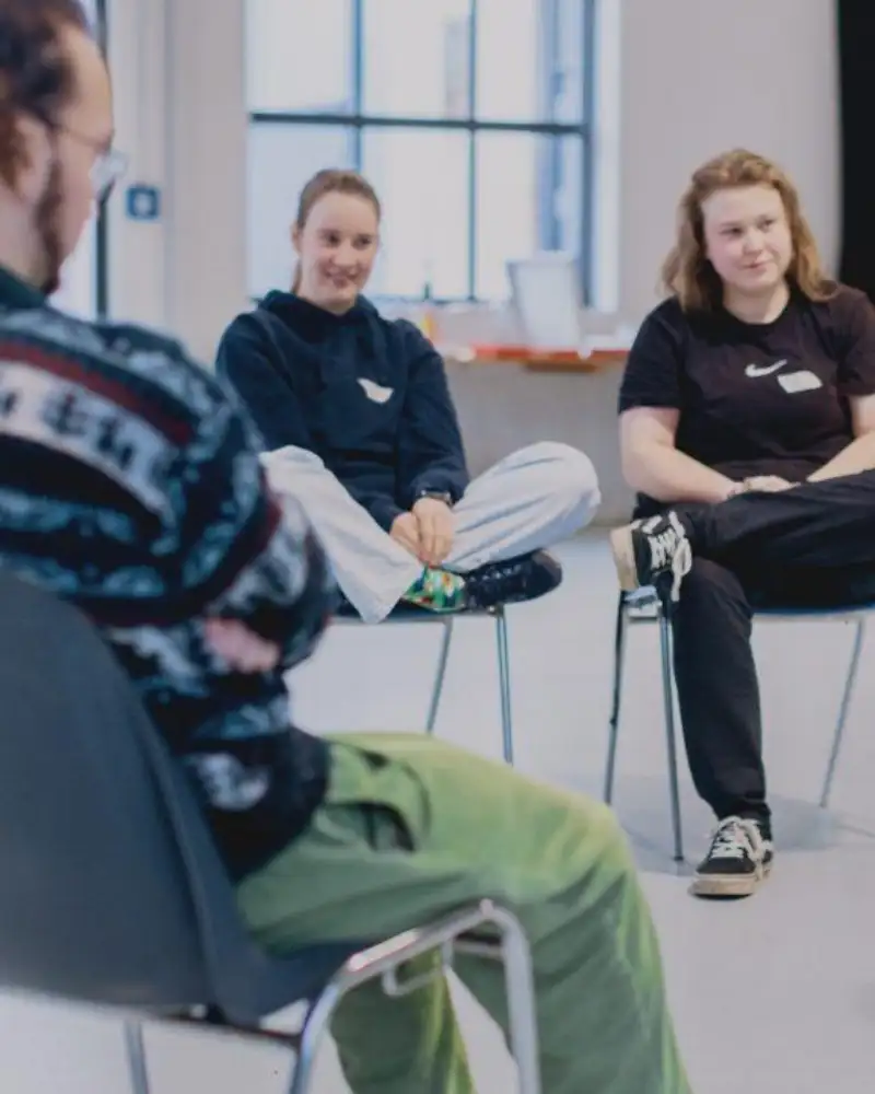 Drei Jugendliche in einem Stuhlkreis