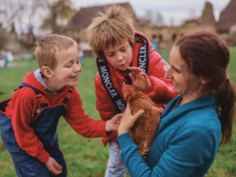 Zwei Kinder und eine Frau mit Huhn