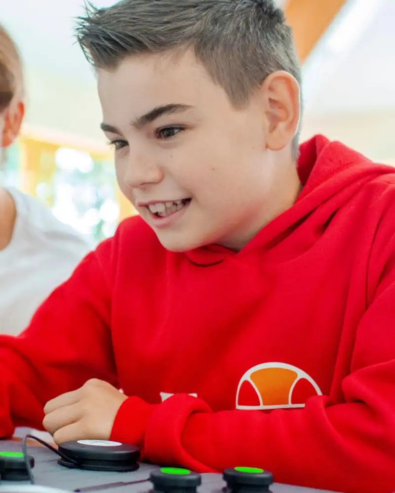 Ein Junge tippt auf einer Computertastatur, ein junger Mann schaut dabei zu.