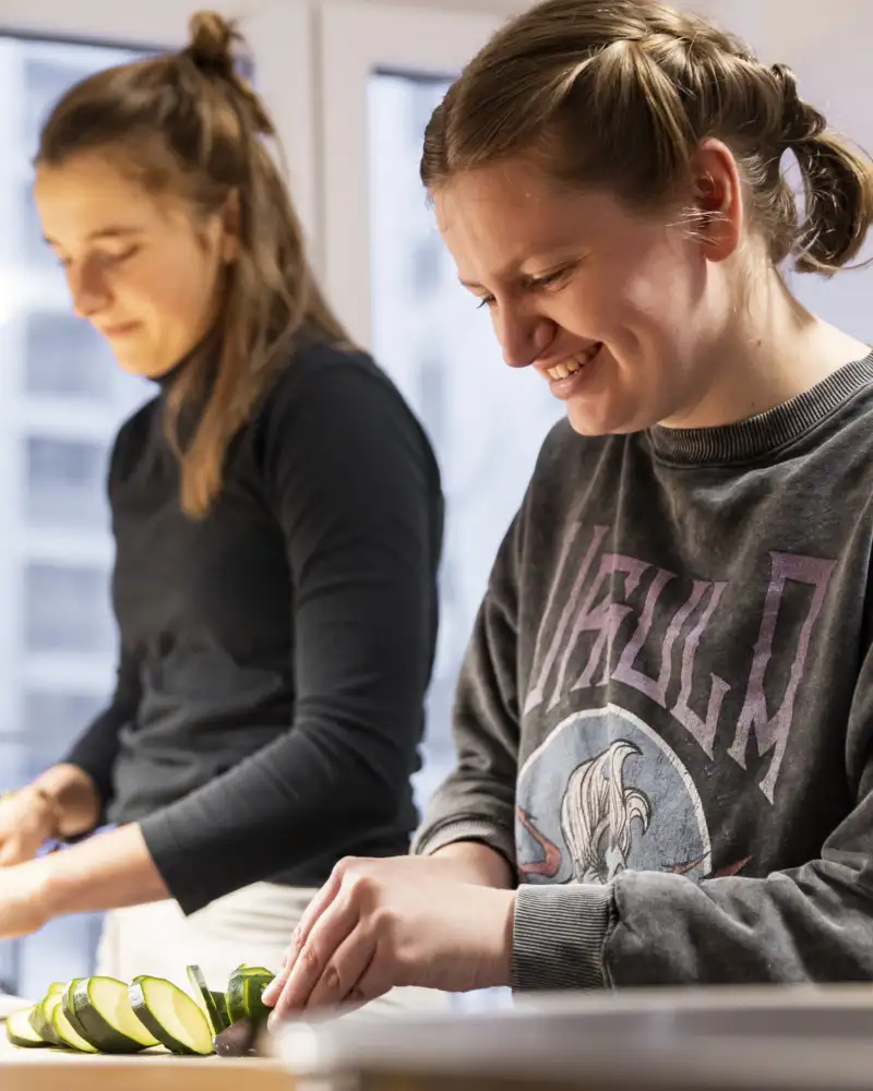 Zwei Frauen schneiden Gurken in einer Küche
