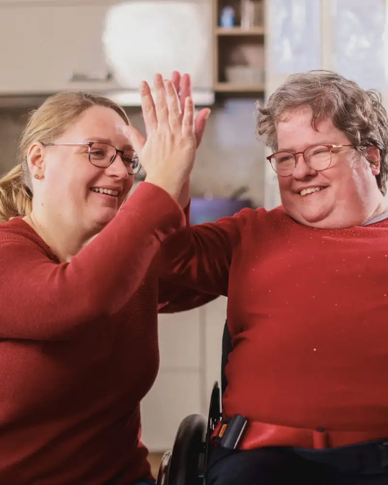 Eine Frau und eine Person im Rollstuhl klatschen sich ab