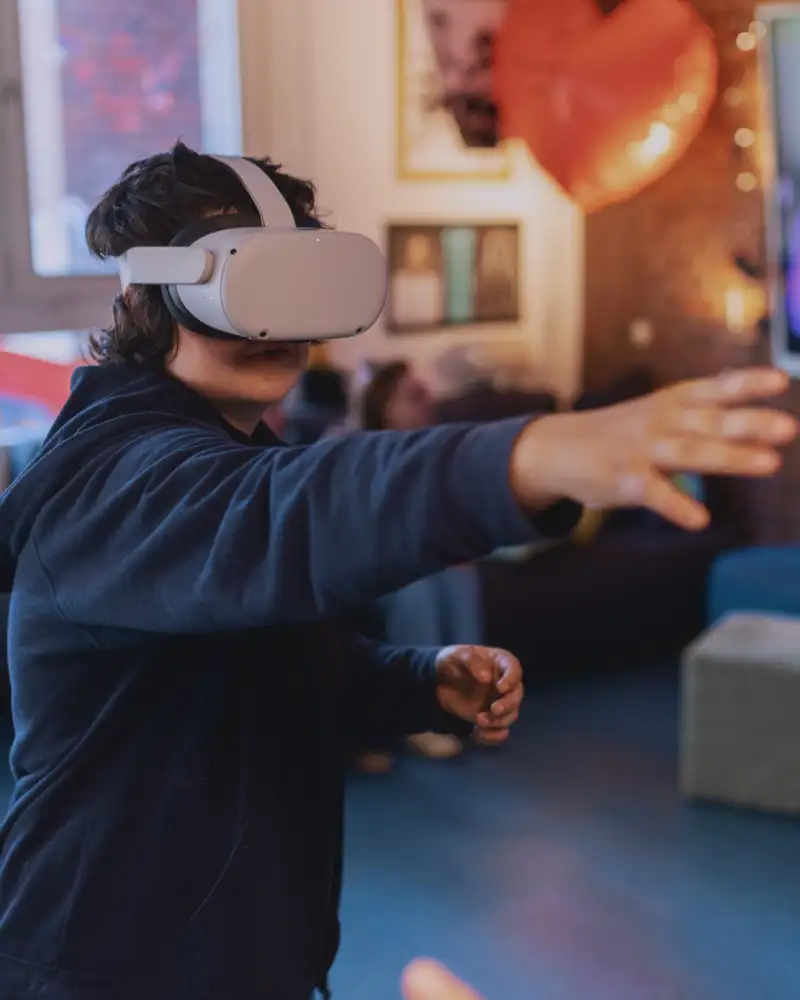 Eine Jugendliche trägt eine VR-Brille und streckt ihren Arm aus.