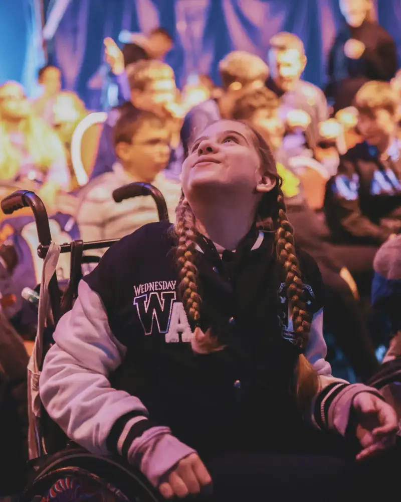 Ein Mädchen im Rollstuhl im vollen Zuschauerraum eines Zirkus