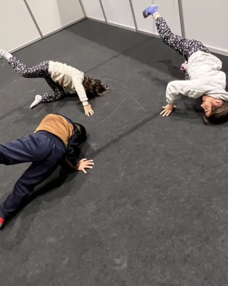 Drei Kinder üben Breakdance-Moves am Boden.