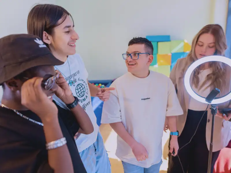 Drei Jugendliche stehen zusammen, neben ihnen steht eine junge Frau.