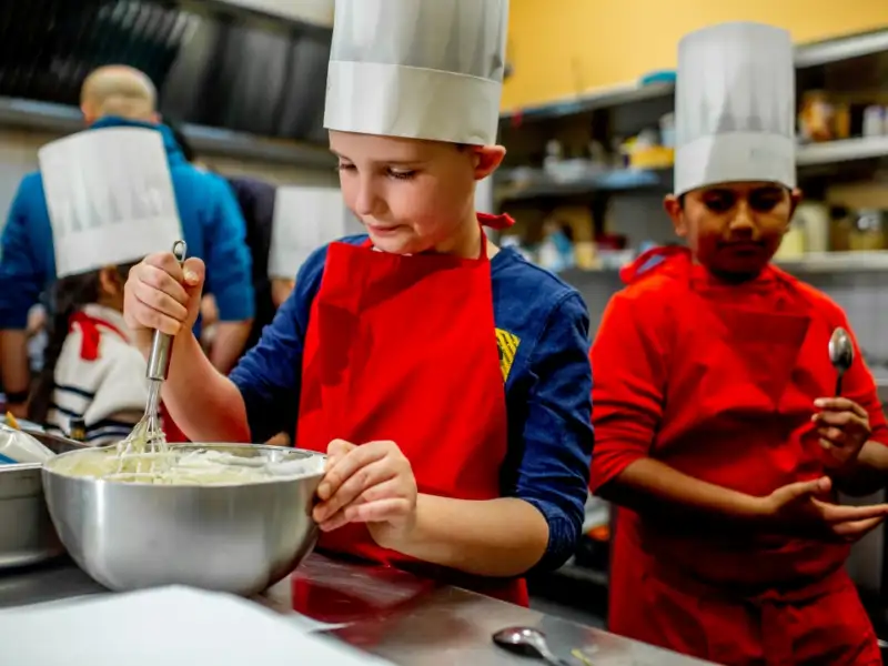 Zwei Jungs mit Bäckermützen backen etwas
