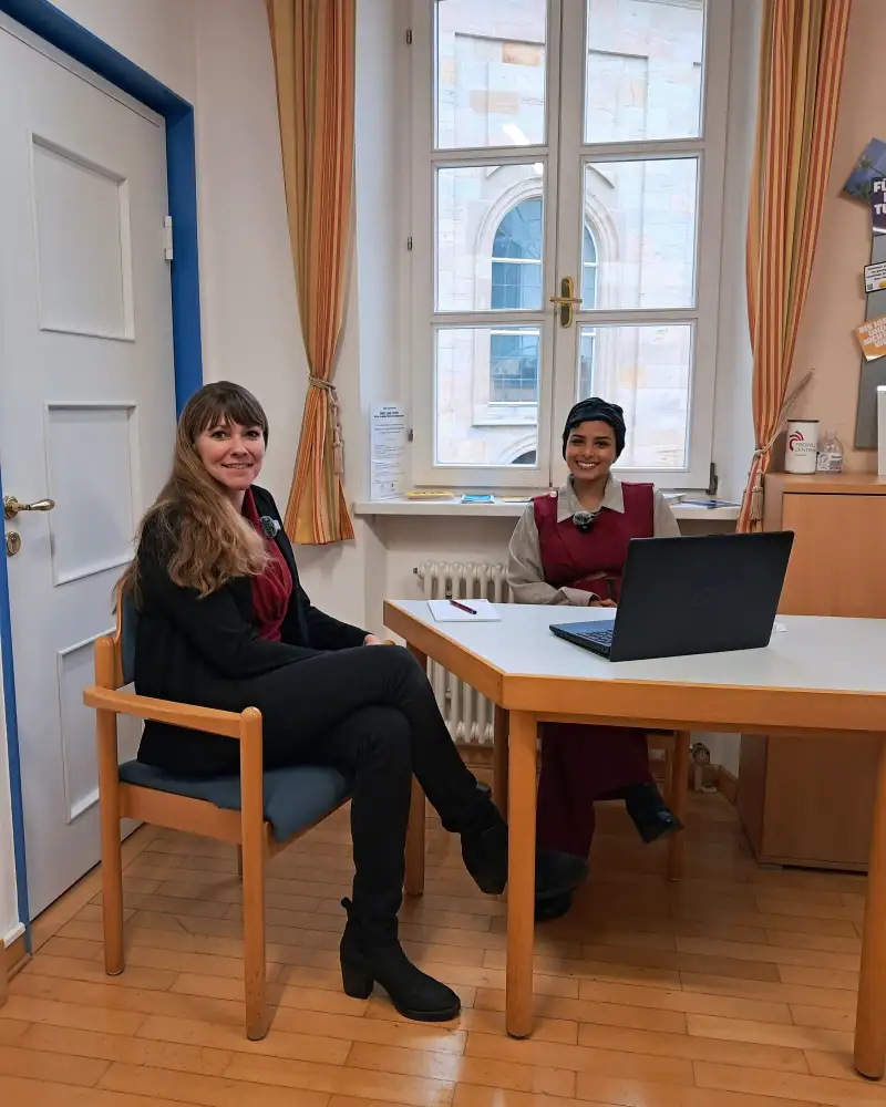 Zwei Frauen sitzen an einem Tisch mit Laptop