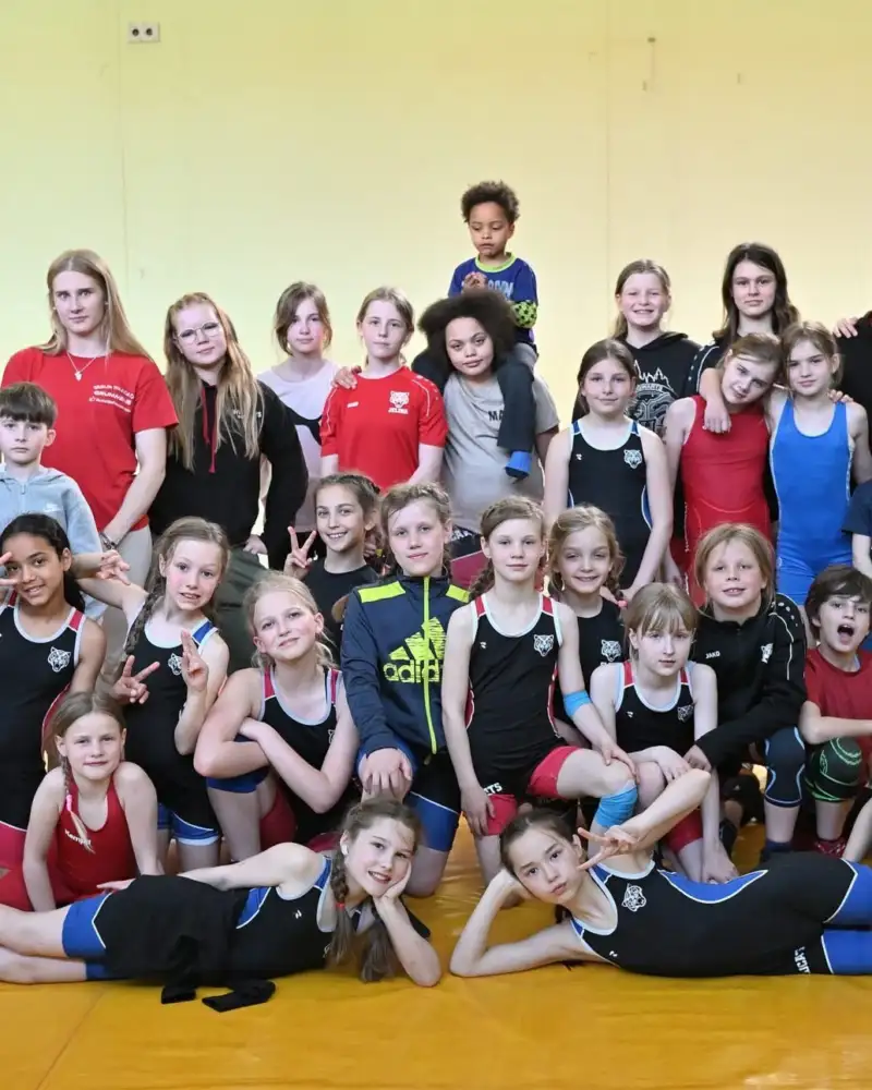Gruppenbild mit Mädchen im Sportkleidung und wenigen Erwachsenen.