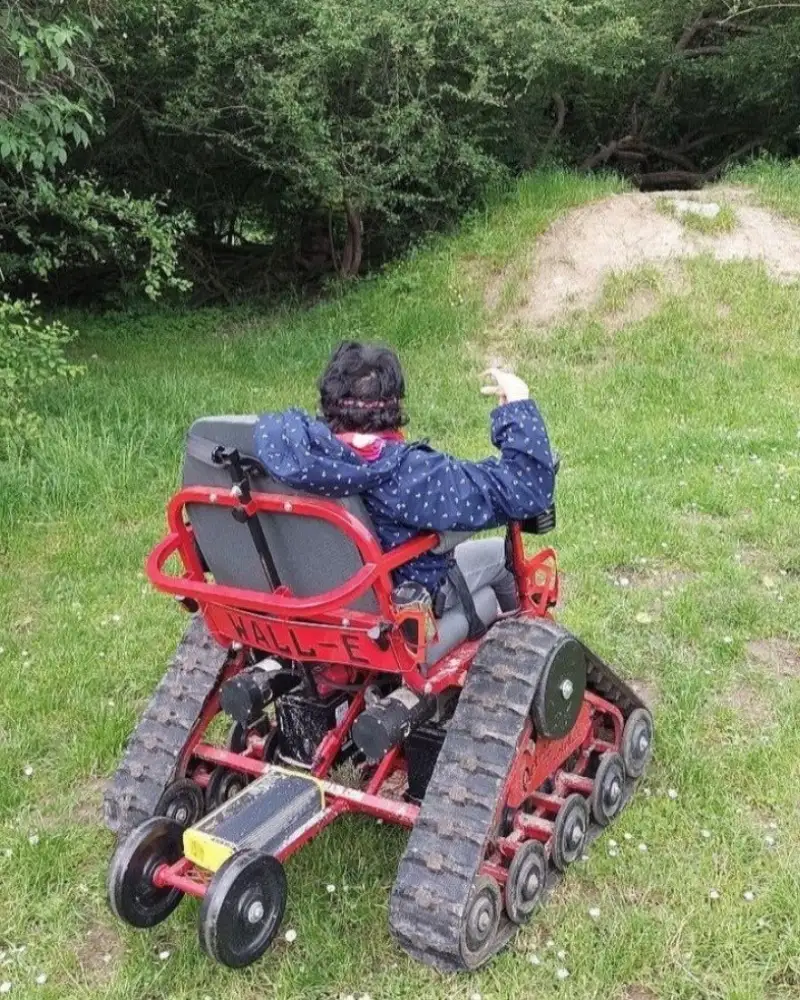 Eine Person im Gelände-Rollstuhl, von hinten fotografiert