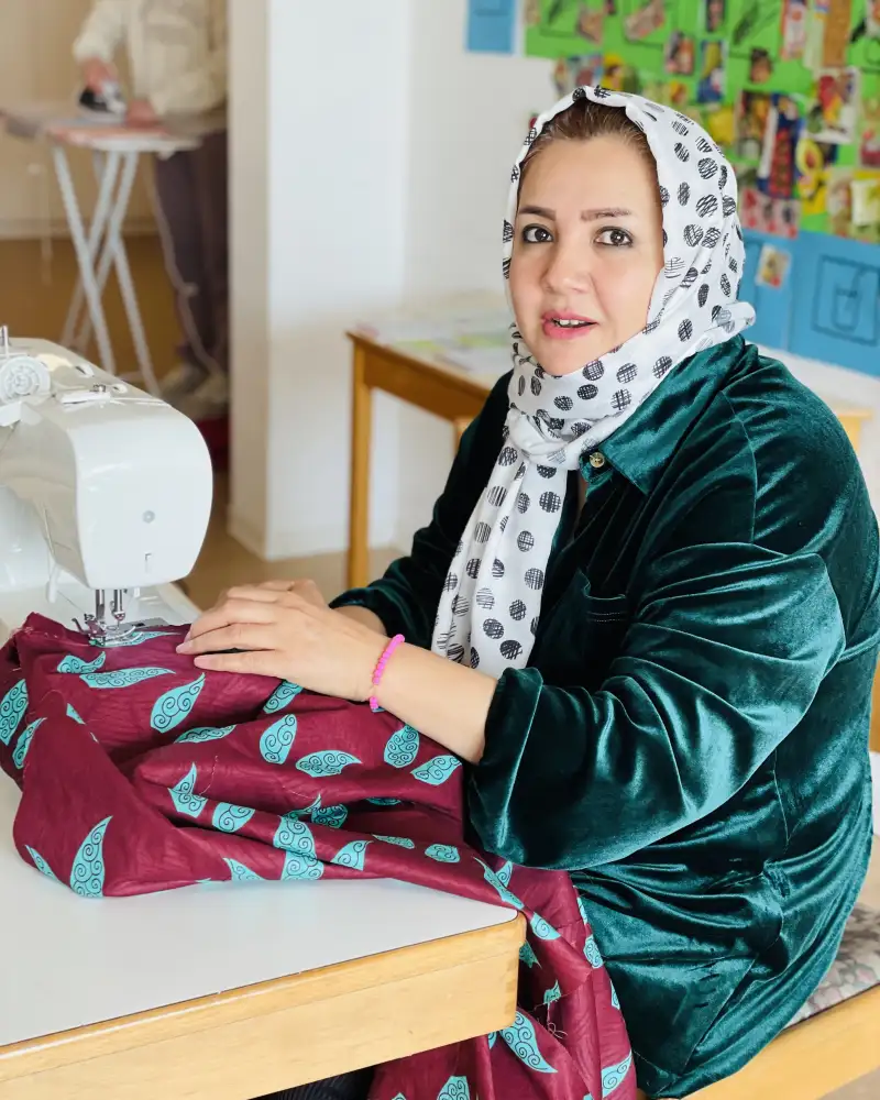 Eine Frau mit Kopftuch an einer Nähmaschine