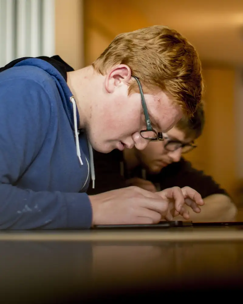 Ein junger Mann beugt sich über ein Smartphone.