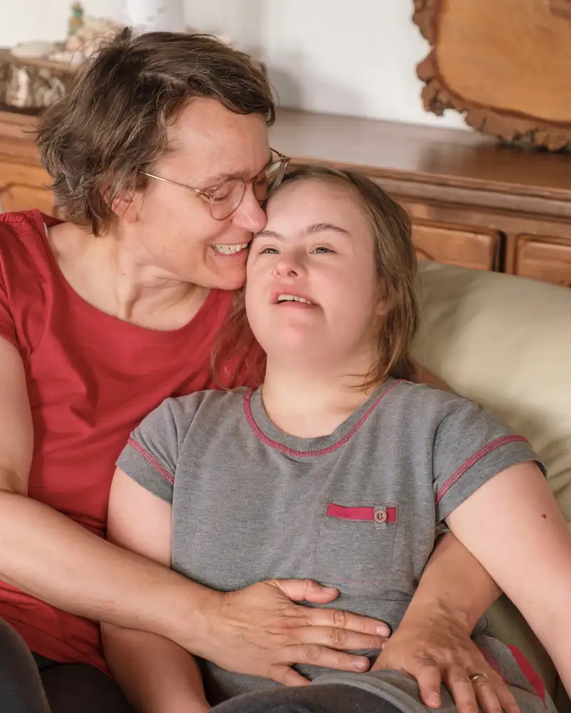 Eine Mutter umarmt ihre Tochter mit Downsyndrom.